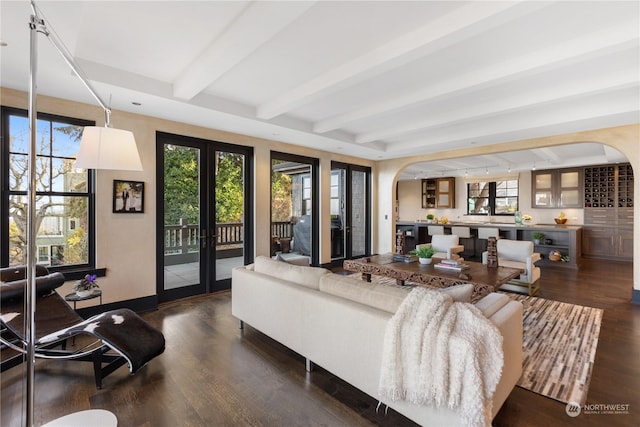 living room with a wealth of natural light, french doors, beamed ceiling, and dark wood-type flooring