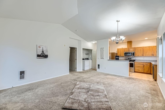 kitchen with stainless steel appliances, vaulted ceiling, washer and clothes dryer, pendant lighting, and a chandelier