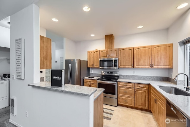 kitchen with sink, light stone countertops, kitchen peninsula, stainless steel appliances, and washer / clothes dryer