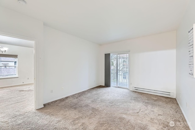 carpeted spare room with a notable chandelier and a baseboard heating unit