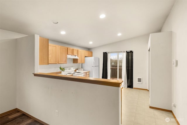 kitchen with kitchen peninsula, white appliances, light brown cabinets, light hardwood / wood-style flooring, and lofted ceiling