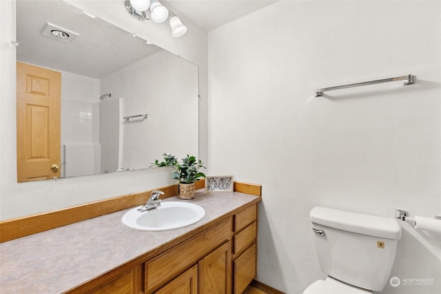 bathroom with walk in shower, vanity, and toilet