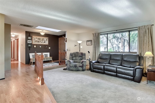 living room with a skylight, a textured ceiling, and hardwood / wood-style flooring