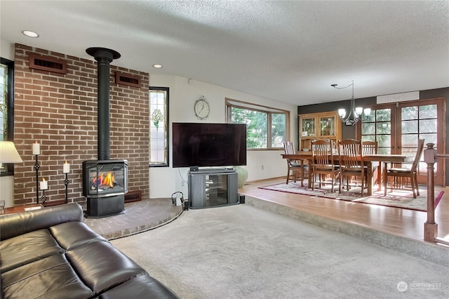 living room with a chandelier, a textured ceiling, hardwood / wood-style flooring, and a wood stove