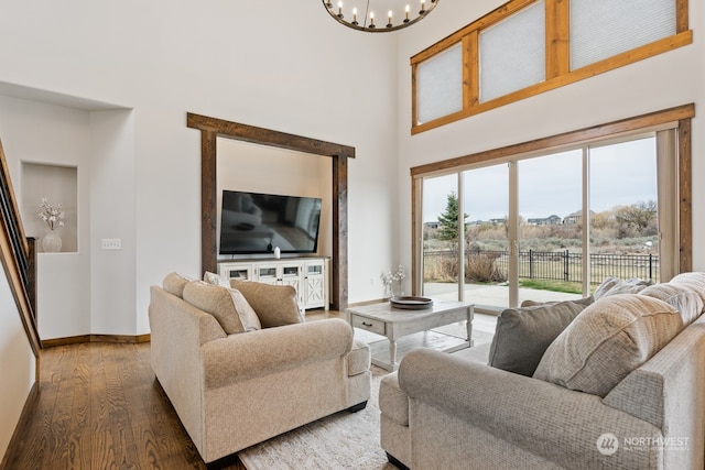 living room featuring dark wood-type flooring, a high ceiling, and an inviting chandelier