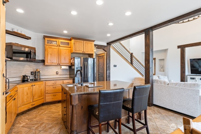 kitchen featuring sink, a kitchen island with sink, decorative backsplash, a breakfast bar, and appliances with stainless steel finishes