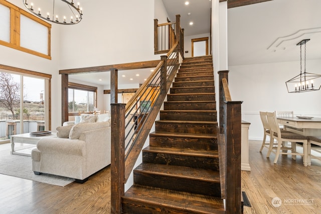 staircase with wood-type flooring and a towering ceiling