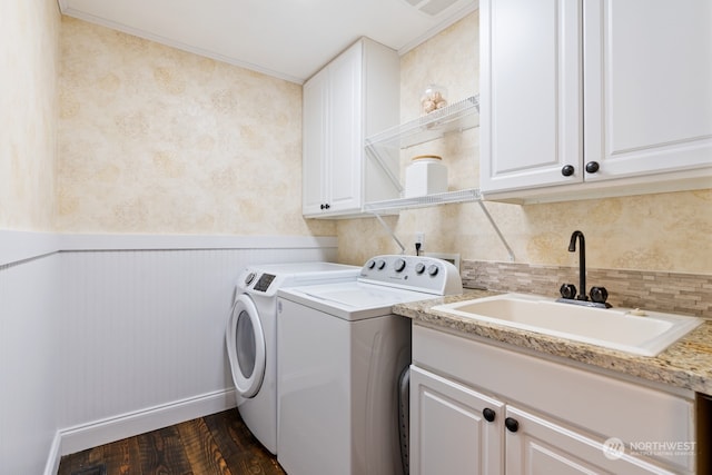 clothes washing area featuring cabinets, dark hardwood / wood-style flooring, ornamental molding, sink, and washing machine and clothes dryer