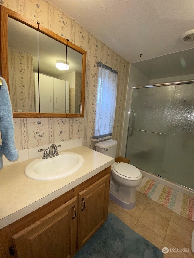 bathroom featuring toilet, an enclosed shower, a textured ceiling, vanity, and tile patterned flooring