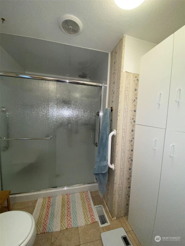 bathroom featuring toilet, tile patterned flooring, and a shower with door