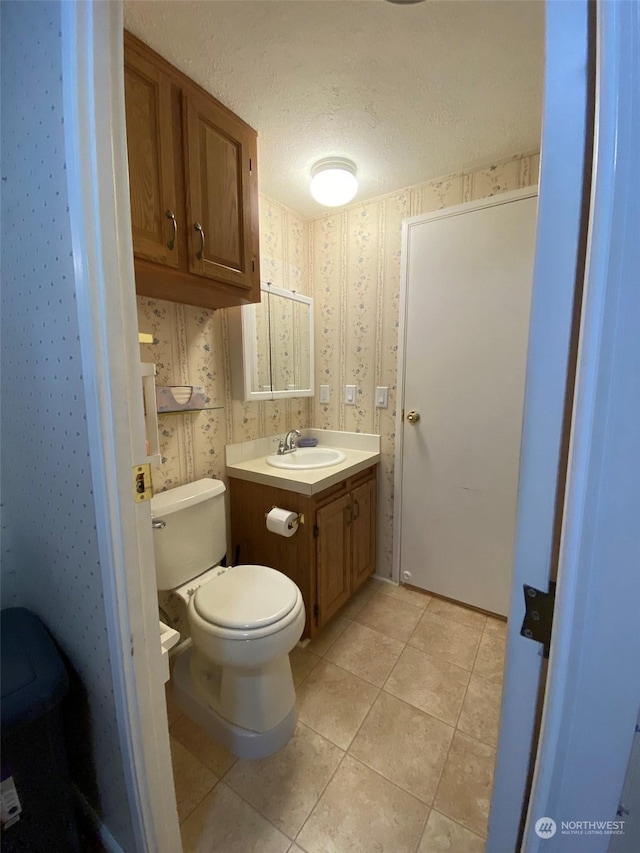 bathroom with tile patterned flooring, vanity, a textured ceiling, and toilet