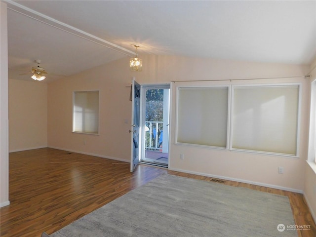 empty room with lofted ceiling, wood-type flooring, and ceiling fan with notable chandelier