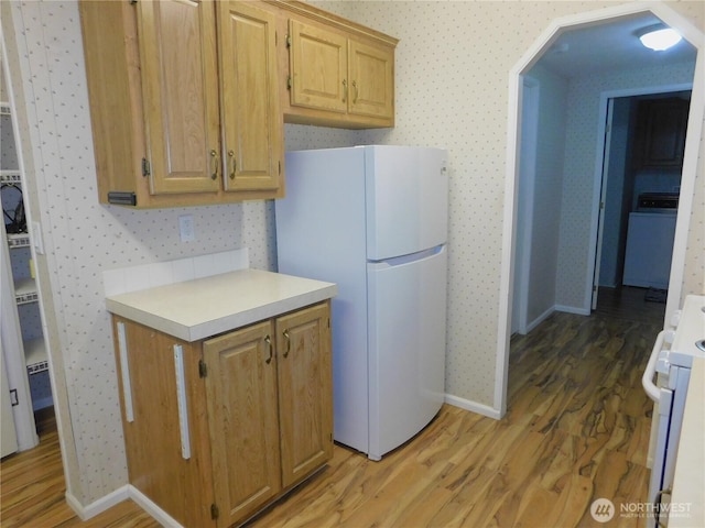 kitchen with washer / clothes dryer, wood-type flooring, and white appliances