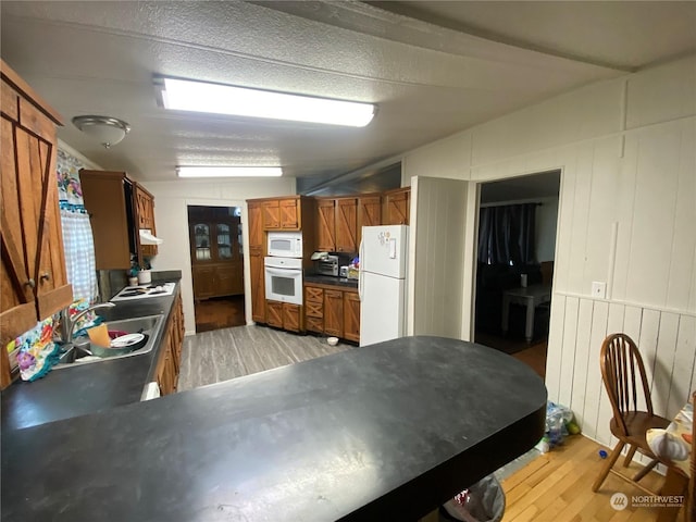 kitchen featuring a textured ceiling, sink, white appliances, and light wood-type flooring