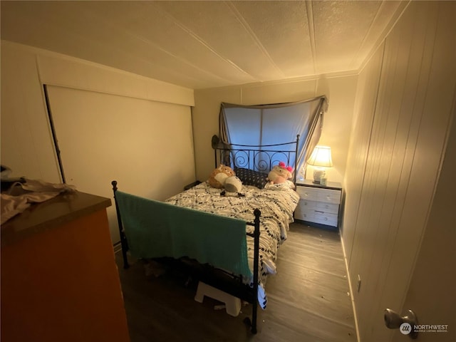 bedroom with wooden walls and wood-type flooring