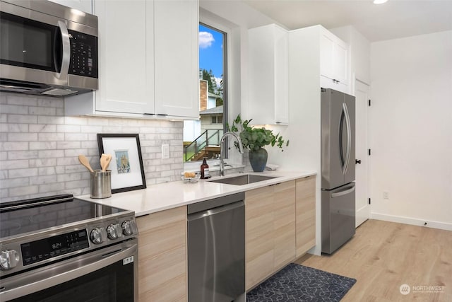 kitchen featuring white cabinets, sink, appliances with stainless steel finishes, and light hardwood / wood-style flooring