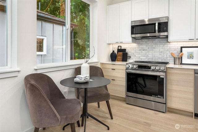 kitchen with stainless steel appliances, tasteful backsplash, light hardwood / wood-style flooring, light brown cabinetry, and white cabinets