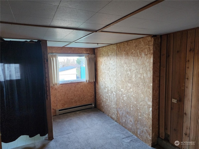 carpeted spare room with a baseboard heating unit