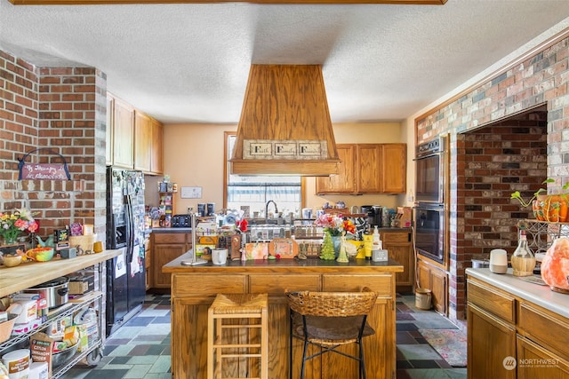 kitchen with double oven, black refrigerator with ice dispenser, a center island, and a breakfast bar