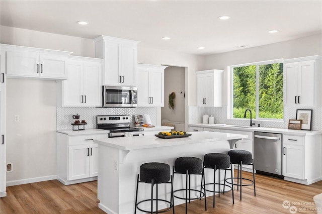 15507 65th Avenue Ct E, Puyallup, WA 98375 - kitchen featuring appliances with stainless steel finishes, light countertops, decorative backsplash, a breakfast bar area, and white cabinetry
