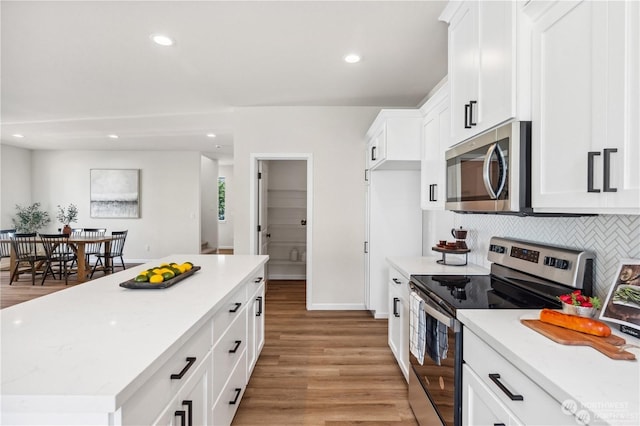 15507 65th Avenue Ct E, Puyallup, WA 98375 - kitchen with stainless steel appliances, backsplash, light wood finished floors, white cabinets, and a kitchen island
