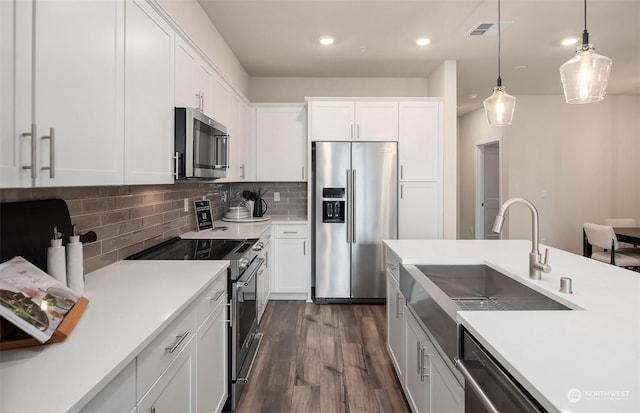 kitchen with hanging light fixtures, white cabinetry, appliances with stainless steel finishes, and sink