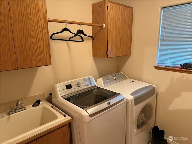 clothes washing area with cabinets, separate washer and dryer, and sink