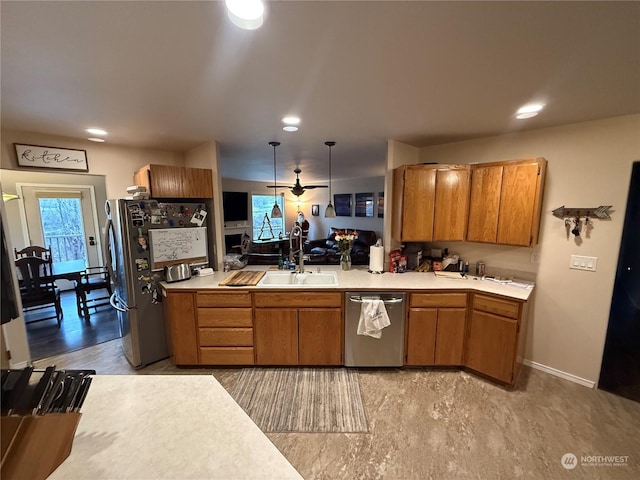 kitchen with kitchen peninsula, appliances with stainless steel finishes, sink, decorative light fixtures, and light hardwood / wood-style floors