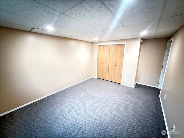 unfurnished bedroom featuring a closet, a drop ceiling, and carpet floors