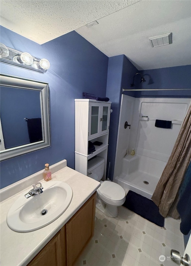 bathroom featuring vanity, curtained shower, toilet, and a textured ceiling