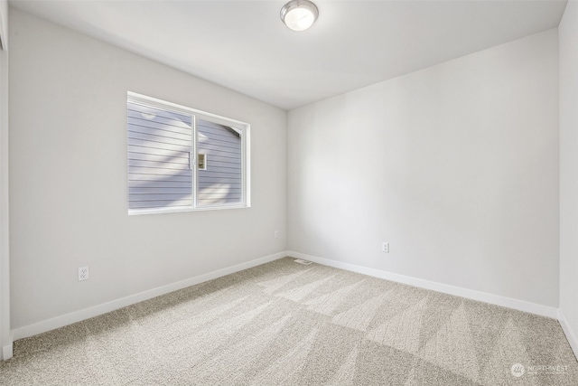 carpeted empty room featuring baseboards