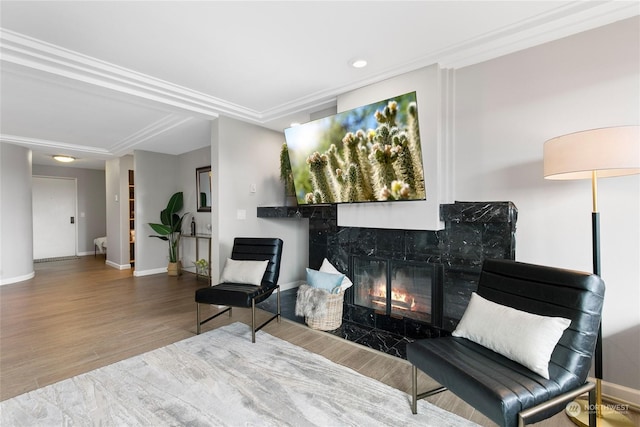 sitting room with hardwood / wood-style flooring, crown molding, and a fireplace