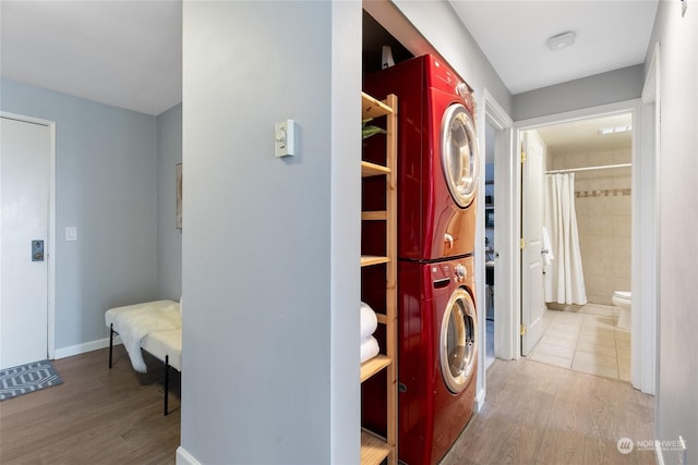 laundry area with stacked washer / dryer and light wood-type flooring