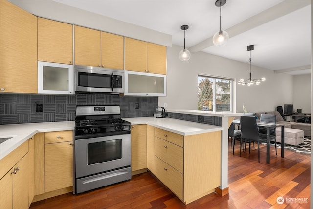 kitchen with kitchen peninsula, decorative backsplash, dark wood-type flooring, and appliances with stainless steel finishes