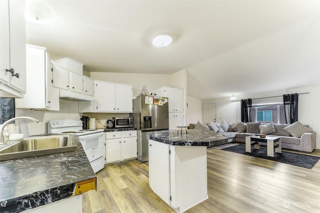 kitchen with appliances with stainless steel finishes, light wood-type flooring, sink, white cabinets, and lofted ceiling