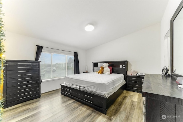 bedroom featuring light hardwood / wood-style floors and lofted ceiling