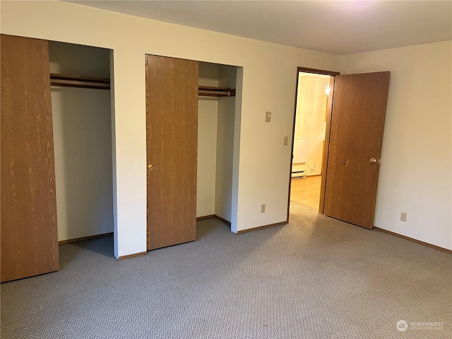 unfurnished bedroom featuring light colored carpet and two closets