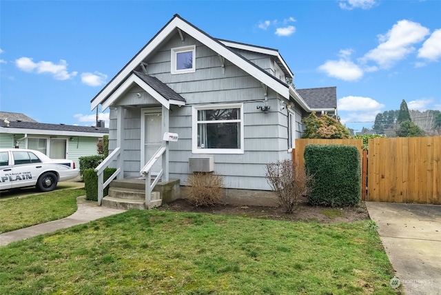 bungalow-style home featuring an AC wall unit and a front lawn