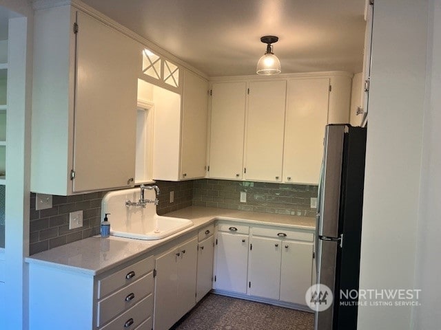 kitchen featuring white cabinetry, sink, stainless steel refrigerator, and tasteful backsplash