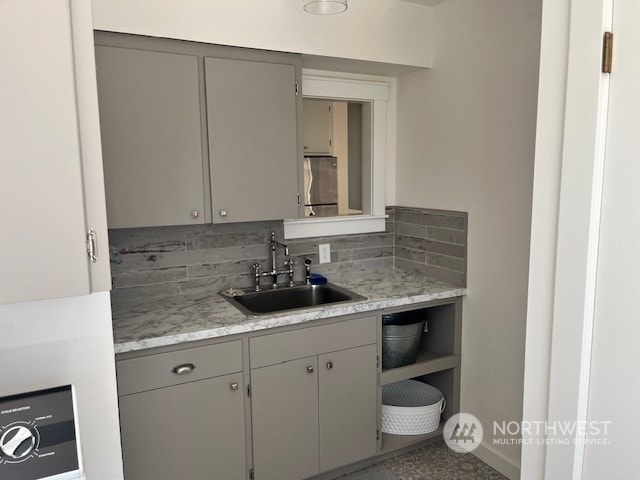 kitchen with gray cabinets, decorative backsplash, and sink