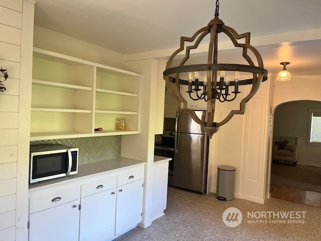 kitchen featuring pendant lighting, white cabinetry, stainless steel appliances, and a chandelier