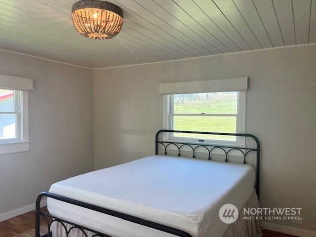 bedroom with multiple windows, crown molding, wooden ceiling, and hardwood / wood-style flooring