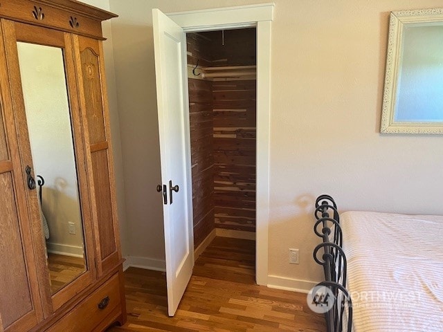 unfurnished bedroom with hardwood / wood-style flooring, wooden walls, and a closet