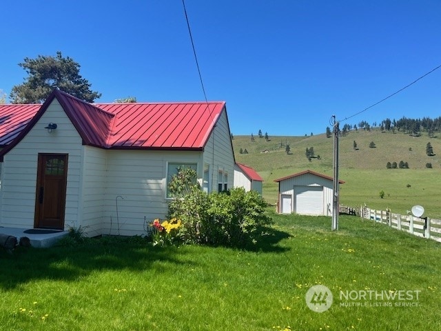view of home's exterior featuring an outbuilding, a rural view, a garage, and a lawn