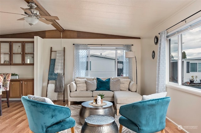 living room with vaulted ceiling with beams, ceiling fan, and light hardwood / wood-style floors