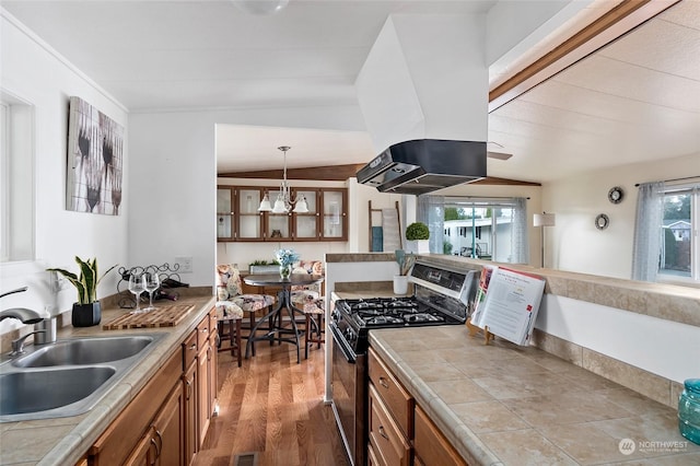 kitchen featuring stainless steel gas stove, tile counters, plenty of natural light, and sink