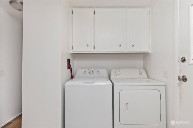 clothes washing area with cabinets, independent washer and dryer, and wood-type flooring