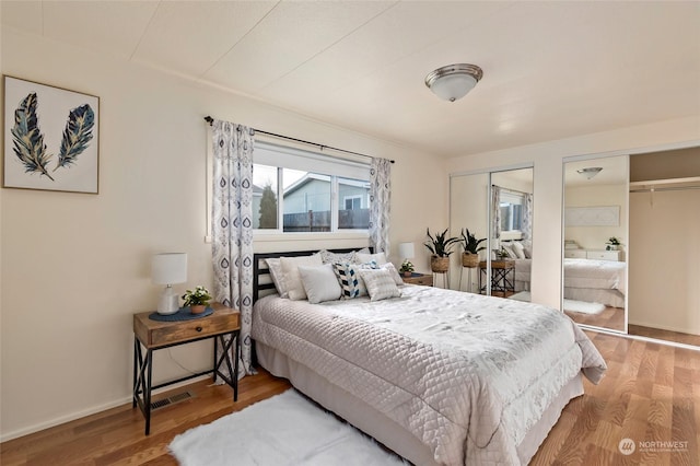 bedroom with multiple closets and hardwood / wood-style flooring