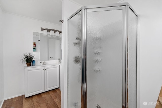 bathroom featuring hardwood / wood-style floors, vanity, walk in shower, and crown molding