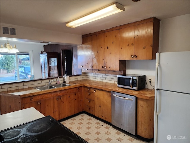 kitchen featuring pendant lighting, an inviting chandelier, sink, tasteful backsplash, and stainless steel appliances